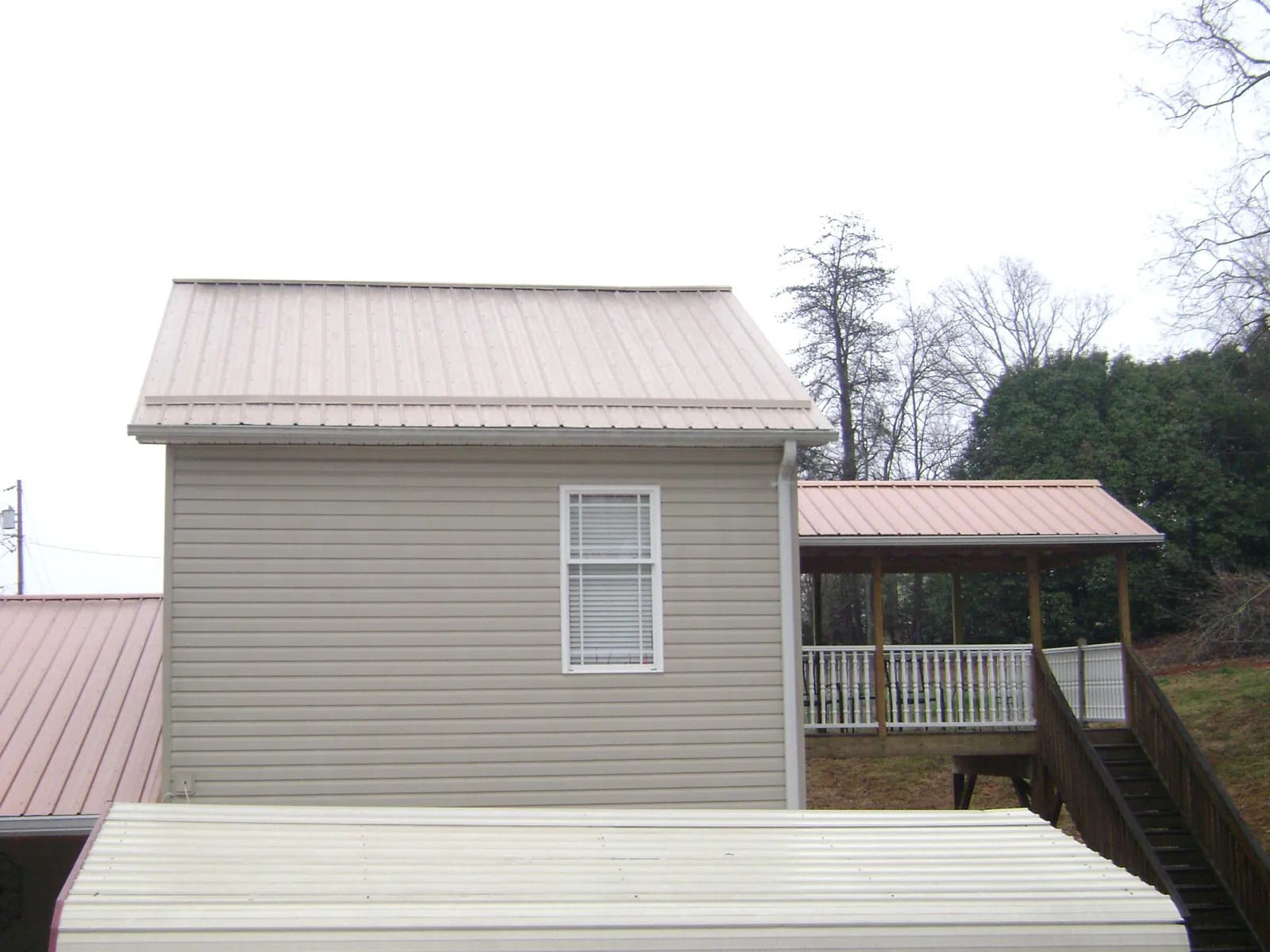 Tan metal roofs on a two story addition and attached porch, from a Roof Replacement job in Prattville