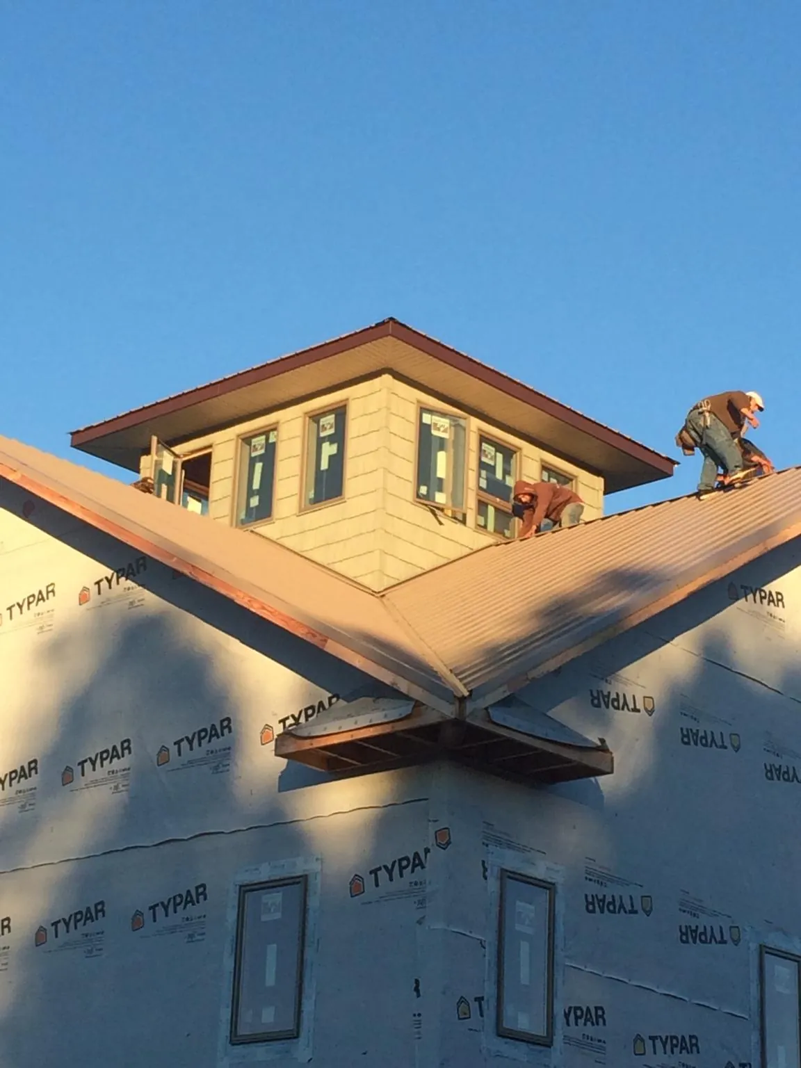 Roofers working around a rooftop cupola on a new metal roof at sunset — Roof Waterproofing in Prattville by Roofing Brothers